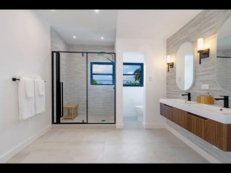 The primary bathroom, with its own private toilet room, a floating twin sink vanity, a soaking tub, and a sliding glass rain shower.