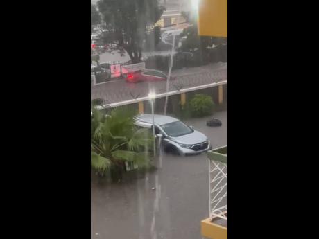 The Robinsons’ car being swept away by floodwaters in New Kingston.