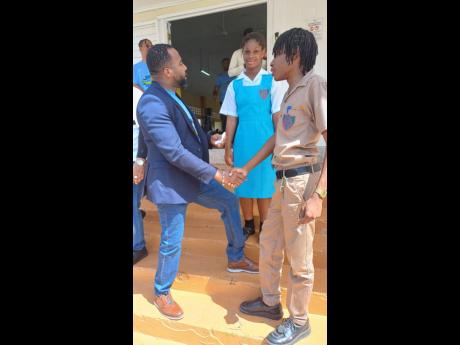Chief Executive Officer of the Universal Service Fund (USF), Charlton McFarlane (left), greets grade 11 student at William Knibb Memorial High School in Trelawny, Amere Pugh (right), at the USF Influencer Creative Workshop held at the St Hilda’s High Sch