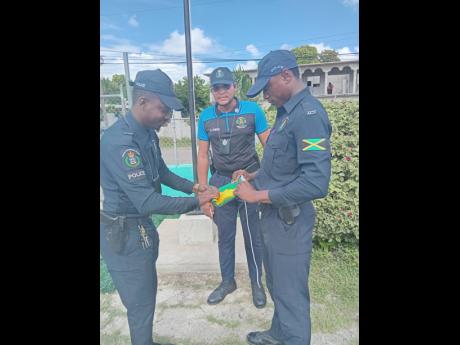 Credit: Rasbert Turner Police personnel prepare the Jamaican flag to be raised for the first time at the Harrison’s Preparatory School in St Catherine.
