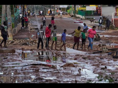 Credit: AP People walk through Santa Cruz, Jamaica after Hurricane Melissa passed.