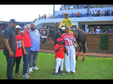 Credit: Anthony Minott
Supreme Ventures Racing and Entertainment Limited’s chairman Solomon Sharpe (fourth left) hugs trainer Philip Feanny after his charge RIDEALLDAY, with jockey Paul Francis in the saddle, parades in the winners enclosure with winning connections following
