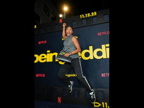 Basketball player Angel McCoughtry is caught in a dunk pose on the blue carpet. 