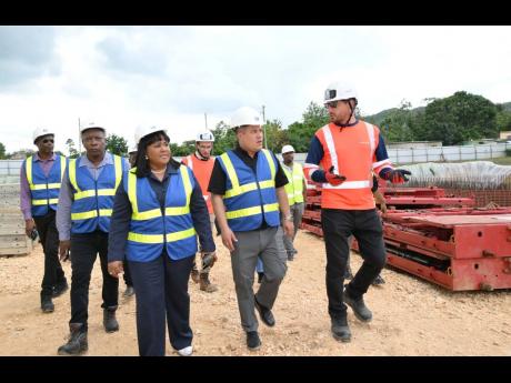 Minister of Water, Environment and Climate Change, Matthew Samuda (centre), along with Member of Parliament for St Catherine North Central, Natalie Neita-Garvey (left), and Project Manager with Vinci Construction, Thomas Savary (right), tour the Rio Cobre 