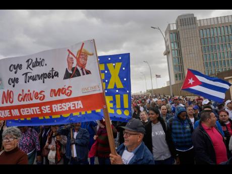 People holding a banner against President Donald Trump, march outside the U.S. Embassy to protest the killing of Cuban officers during the U.S. operation that captured Venezuelan President Nicolas Maduro, in Havana, Cuba, Friday, Jan. 16.