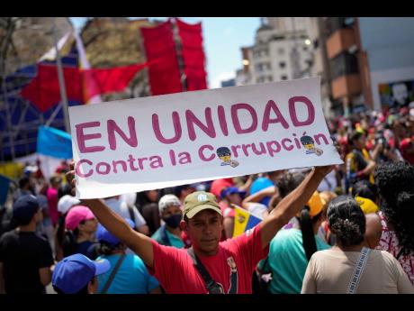 A government supporter holds a sign with a message that reads in Spanish: "In unity against corruption", during a rally against corruption, in Caracas, Venezuela, Saturday, March 25, 2023. (AP Photo/Matias Delacroix, File)
